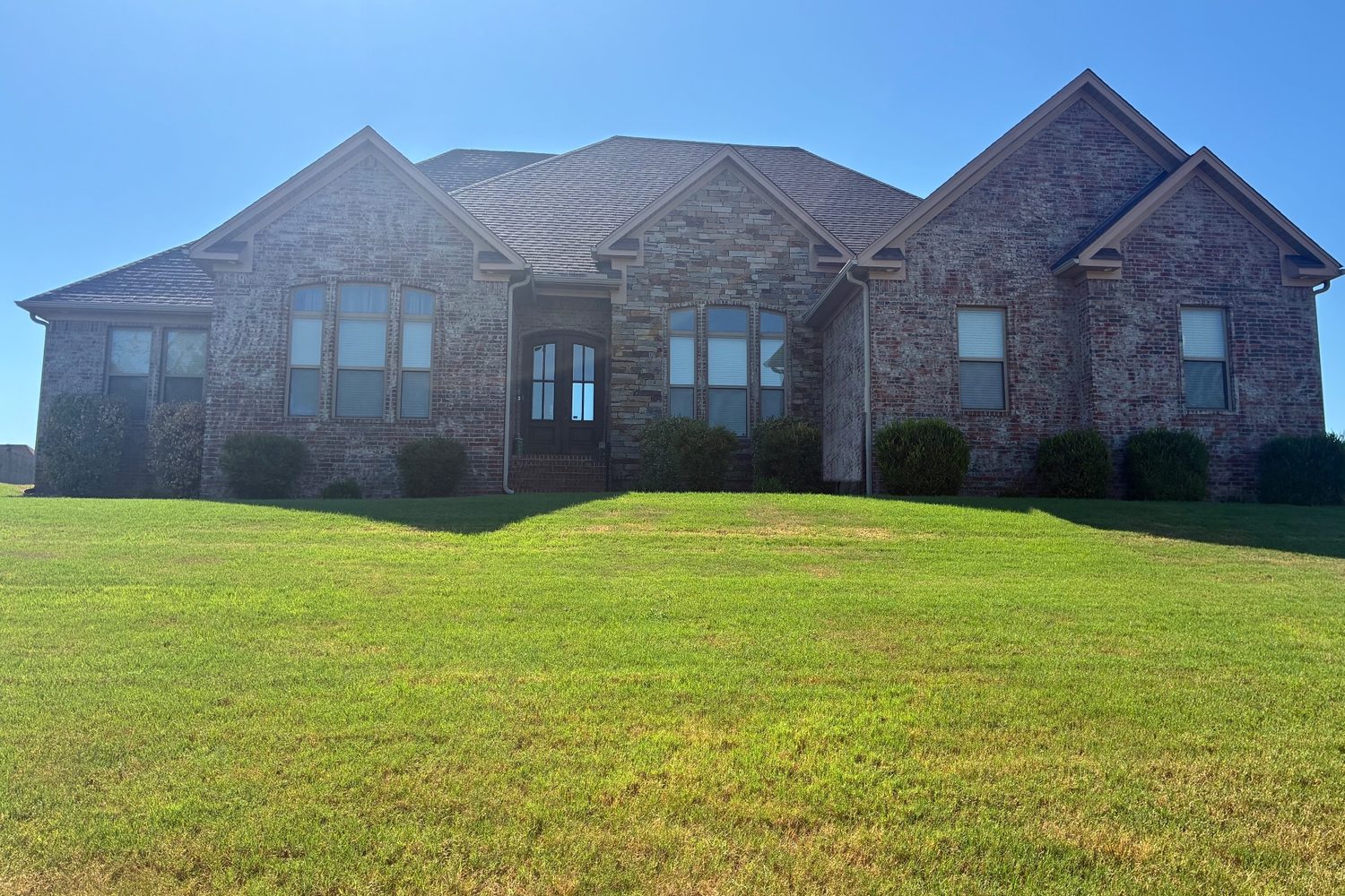Brick and stone home with a finished architectural shingle roof installed by SMI Roofing
